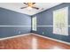 A blue bedroom with two windows, hardwood floors, and a ceiling fan at 105 Kirkland Ct, Archer Lodge, NC 27527