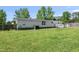 Sprawling backyard with green grass, mature trees, white siding, and a white wooden deck at 109 Winding Creek Dr, Youngsville, NC 27596