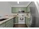 Well-lit kitchen featuring green cabinets, stainless steel appliances, and granite countertops at 11 Stone Village, Durham, NC 27704