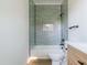 Bathroom featuring a tiled tub and shower with a white toilet and light-colored wood-look floors at 1124 Upchurch St, Raleigh, NC 27610