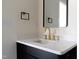 Bathroom featuring black cabinets, gold fixtures, and a white sink with black framed mirror at 1124 Upchurch St, Raleigh, NC 27610