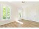 Bright bedroom featuring wood-look floors, white walls, white trim, and two windows offering natural light at 1124 Upchurch St, Raleigh, NC 27610