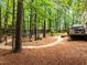 Woodland backyard featuring a wood path, mature trees, and lush greenery creates a serene and inviting outdoor space at 1204 Benoit Pl, Apex, NC 27502