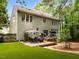 A landscaped backyard featuring a spacious deck with seating, a patio, and mature trees for privacy and relaxation at 1204 Benoit Pl, Apex, NC 27502