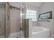 Nicely remodeled bathroom with a glass shower, soaking tub with tile surround and patterned window at 1204 Benoit Pl, Apex, NC 27502