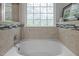 Clean bathroom featuring a soaking tub with tiled surround and decorative frosted window at 1204 Benoit Pl, Apex, NC 27502
