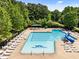 Large community pool featuring multiple swim areas, a water slide, and lounge chairs surrounded by mature trees at 1204 Benoit Pl, Apex, NC 27502