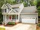 Charming home featuring a two-car garage, red door, and a welcoming front porch with white railings at 1204 Benoit Pl, Apex, NC 27502