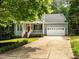 Inviting home with well-manicured lawn, a red front door, and a charming porch with white railings and columns at 1204 Benoit Pl, Apex, NC 27502