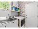 This well-equipped laundry room includes modern washer/dryer, storage shelves and is accented by a rustic brick wall at 1204 Benoit Pl, Apex, NC 27502