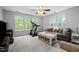 Bright living room with large windows, gray sofa, and a treadmill at 1204 Benoit Pl, Apex, NC 27502