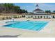 Community pool with a splash fountain and a clubhouse with dark roof shingles in the background at 1223 Brown Velvet Ln, Apex, NC 27523