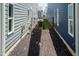A narrow side yard between homes with black metal fence, rocks, and a small patch of grass at 1223 Brown Velvet Ln, Apex, NC 27523