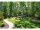 Lush backyard featuring mature trees, green grass, and a stone paver walkway at 12733 Pamplona Dr, Wake Forest, NC 27587