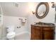 Charming powder room featuring custom vanity, stone countertop, and decorative oval mirror at 12733 Pamplona Dr, Wake Forest, NC 27587