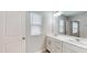 Bright bathroom with double sink vanity, a large mirror, white cabinets and wood look flooring at 1314 Rosepine Dr, Cary, NC 27519