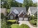 Aerial view of a brick home with a dark roof, green landscaping, and a curved driveway at 156 Yorkchester Way, Raleigh, NC 27615