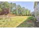 Large backyard with lush green grass, trees, a play set, and a fenced-in area with garden beds at 1808 Capstone Dr, Durham, NC 27713