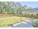Outdoor living space with a covered patio overlooking a sprawling green lawn and bordered by mature trees and a wooden fence at 1808 Capstone Dr, Durham, NC 27713
