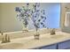 Close up of a modern bathroom with double sinks, decorative flowers, and a neutral color scheme at 1808 Capstone Dr, Durham, NC 27713