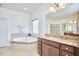 A bathroom featuring a soaking tub with decorative tile and a granite vanity at 1808 Capstone Dr, Durham, NC 27713
