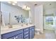 Bright bathroom featuring double sinks, a blue vanity, a window, and a decorative flower arrangement at 1808 Capstone Dr, Durham, NC 27713
