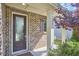Inviting front porch featuring brick accents, a glass door and lush landscaping at 1808 Capstone Dr, Durham, NC 27713