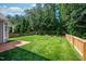 Expansive backyard featuring lush green grass, surrounded by mature trees and a wooden fence, offering privacy at 1908 Woodsdale Dr, Durham, NC 27703