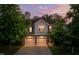 Charming two-story home with gray siding, stone accents, and a two-car garage at dusk at 1908 Woodsdale Dr, Durham, NC 27703