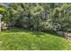 Large backyard featuring a lush green lawn, mature trees, and a wooden privacy fence at 205 Forbes Rd, Wake Forest, NC 27587