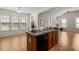 Open-concept kitchen with island, wood cabinets, and adjoining living area filled with natural light at 207 Bell Tower Way, Morrisville, NC 27560