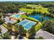 Scenic aerial view showcases community tennis courts, swimming pool, lake, and picturesque common areas with mature tree coverage at 208 Gillean Ln, Holly Springs, NC 27540