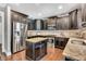 Modern kitchen featuring stainless steel appliances, dark cabinetry, granite countertops, and a central island at 208 Gillean Ln, Holly Springs, NC 27540