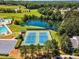 Aerial view of community tennis courts and a pool situated next to a lake with picturesque, mature landscaping and ample parking at 208 Gillean Ln, Holly Springs, NC 27540