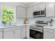 Kitchen featuring grey cabinets, stainless steel appliances, quartz countertops, and subway tile at 2540 Atlantic St, Durham, NC 27707