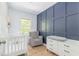 Cozy Bedroom featuring a stylish accent wall, crib, and comfortable glider chair at 3010 Blueberry Ln, Chapel Hill, NC 27516