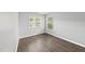 Bright bedroom features hardwood floors and light grey walls, complemented by two sunlit windows at 3033 Remington Oaks Cir, Cary, NC 27519