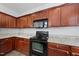 Kitchen with sleek black appliances, granite countertops, and cherry wood cabinets at 3033 Remington Oaks Cir, Cary, NC 27519