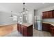 Kitchen with granite island, stainless refrigerator, and cherry wood cabinets with ample storage at 3033 Remington Oaks Cir, Cary, NC 27519