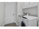 A well-organized laundry room featuring a modern washer and dryer with overhead cabinets and a gray tile floor at 3033 Remington Oaks Cir, Cary, NC 27519