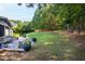 Large grassy backyard with mature trees, featuring patio with dining area, and screened porch at 3209 Bryant Falls Ct, Raleigh, NC 27613