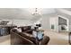 Cozy living room features a large leather couch, chandelier, wet bar, and lots of natural light at 3209 Bryant Falls Ct, Raleigh, NC 27613