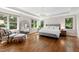 This main bedroom has tray ceilings, hardwood floors, seating, large windows, and neutral tones for a serene retreat at 3209 Bryant Falls Ct, Raleigh, NC 27613