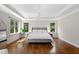 Sun-filled main bedroom features hardwood floors, recessed lights, tray ceiling, and large windows with views of the lush yard at 3209 Bryant Falls Ct, Raleigh, NC 27613