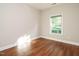 Empty bedroom with wood floors, neutral walls, and a window overlooking the backyard at 33 Juliette Dr, Durham, NC 27713