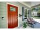 Close-up of the home's entrance with a red door, small bench, and grey window shutters at 3357 Denise St, Durham, NC 27704