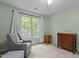 This bedroom features neutral carpet, and a bright window view with a comfortable grey chair at 3401 Scotch Dr, Raleigh, NC 27616