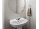 Bathroom with pedestal sink, modern faucet, oval mirror, and towel holder in a neutrally painted room at 4007 Newell Ln, Raleigh, NC 27616