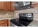 Kitchen featuring stainless steel stove, granite countertops, tile backsplash, and custom wood cabinetry at 4007 Newell Ln, Raleigh, NC 27616