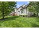 Lush backyard with mature trees, well-manicured lawn, and rear view of the home and deck at 401 Clingstone Ct, Cary, NC 27519